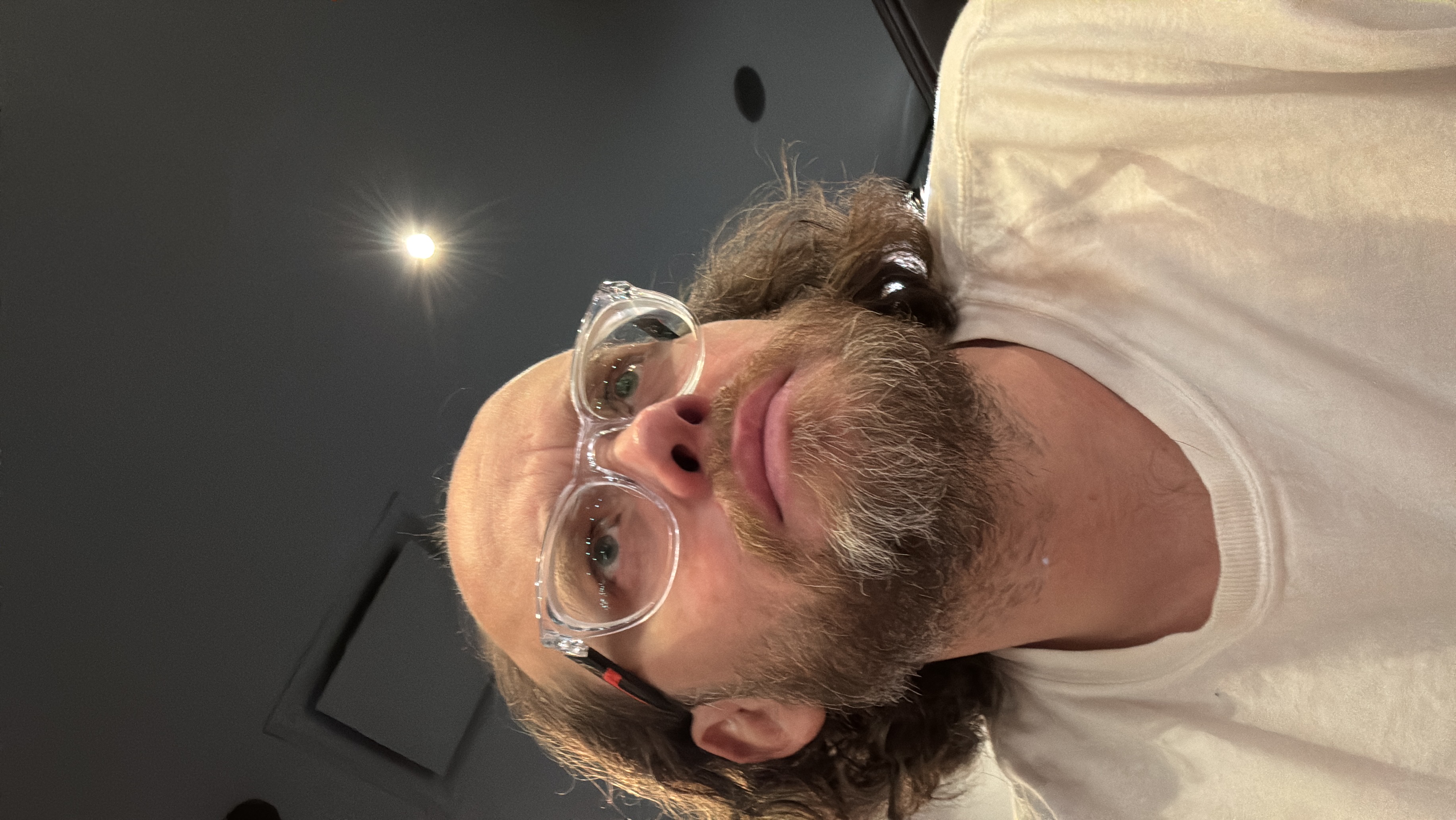 Esteban Rey posa serio en una habitación oscura con gafas transparentes.