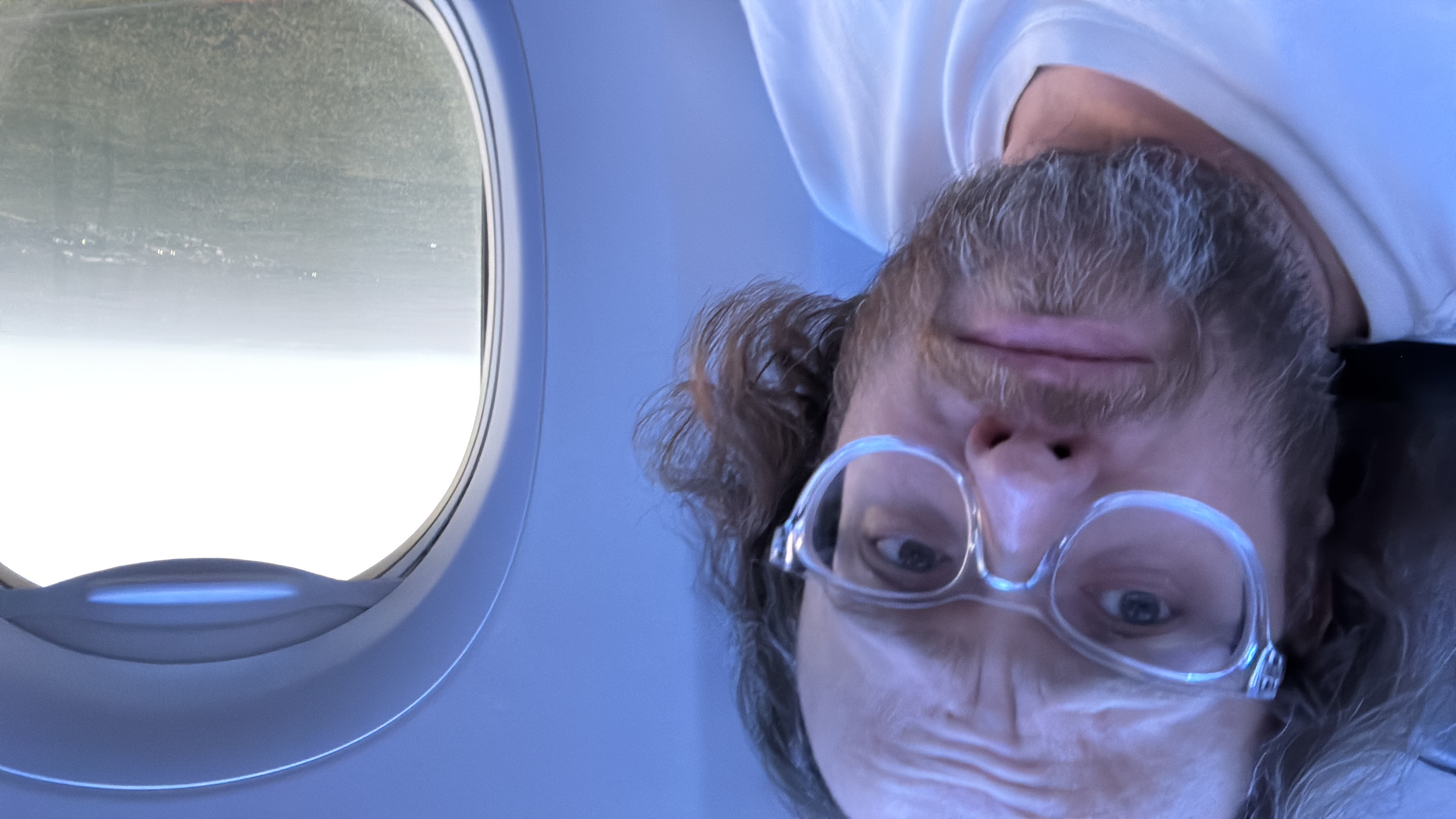 Esteban Rey se relaja en un avión con la cabeza invertida y la ventana abierta.