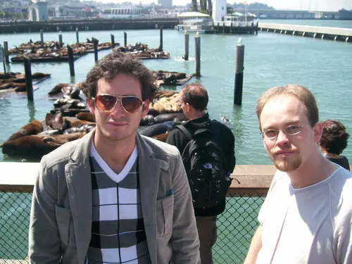 Esteban Rey junto a un amigo en un muelle, con focas en el agua.