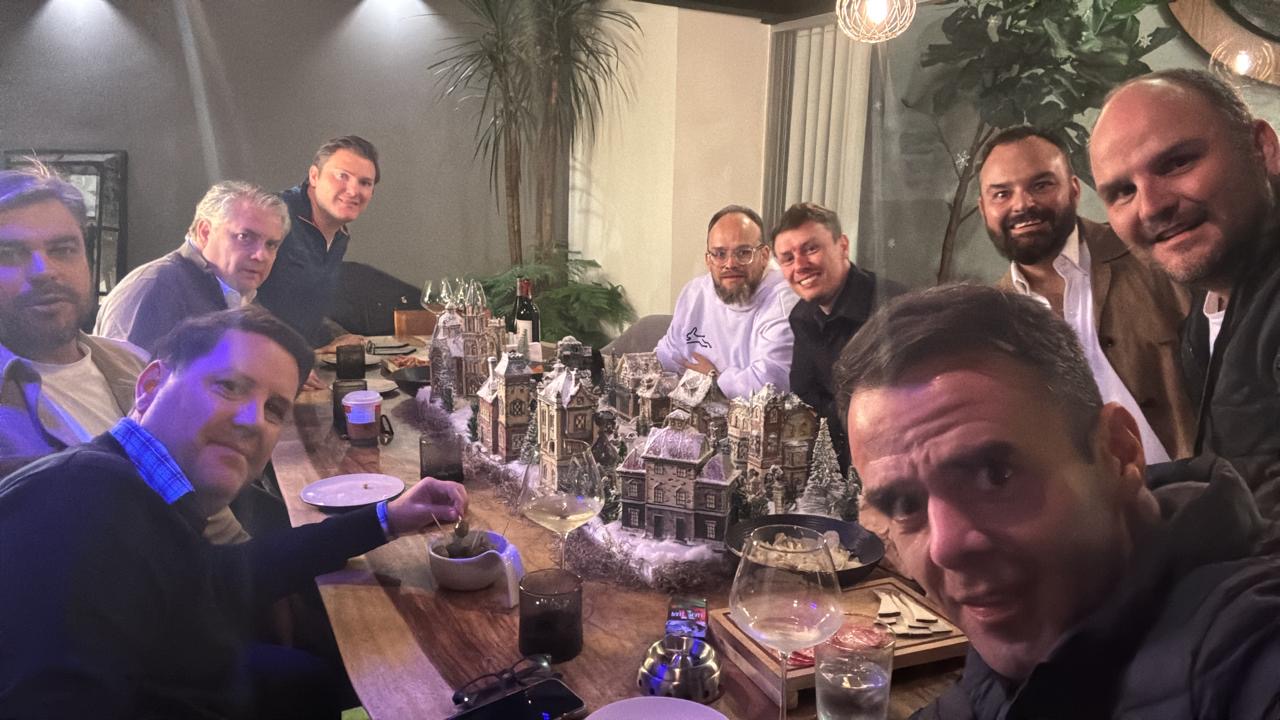 Esteban Rey comparte cena con amigos en una mesa larga con villas de nieve y vino.
